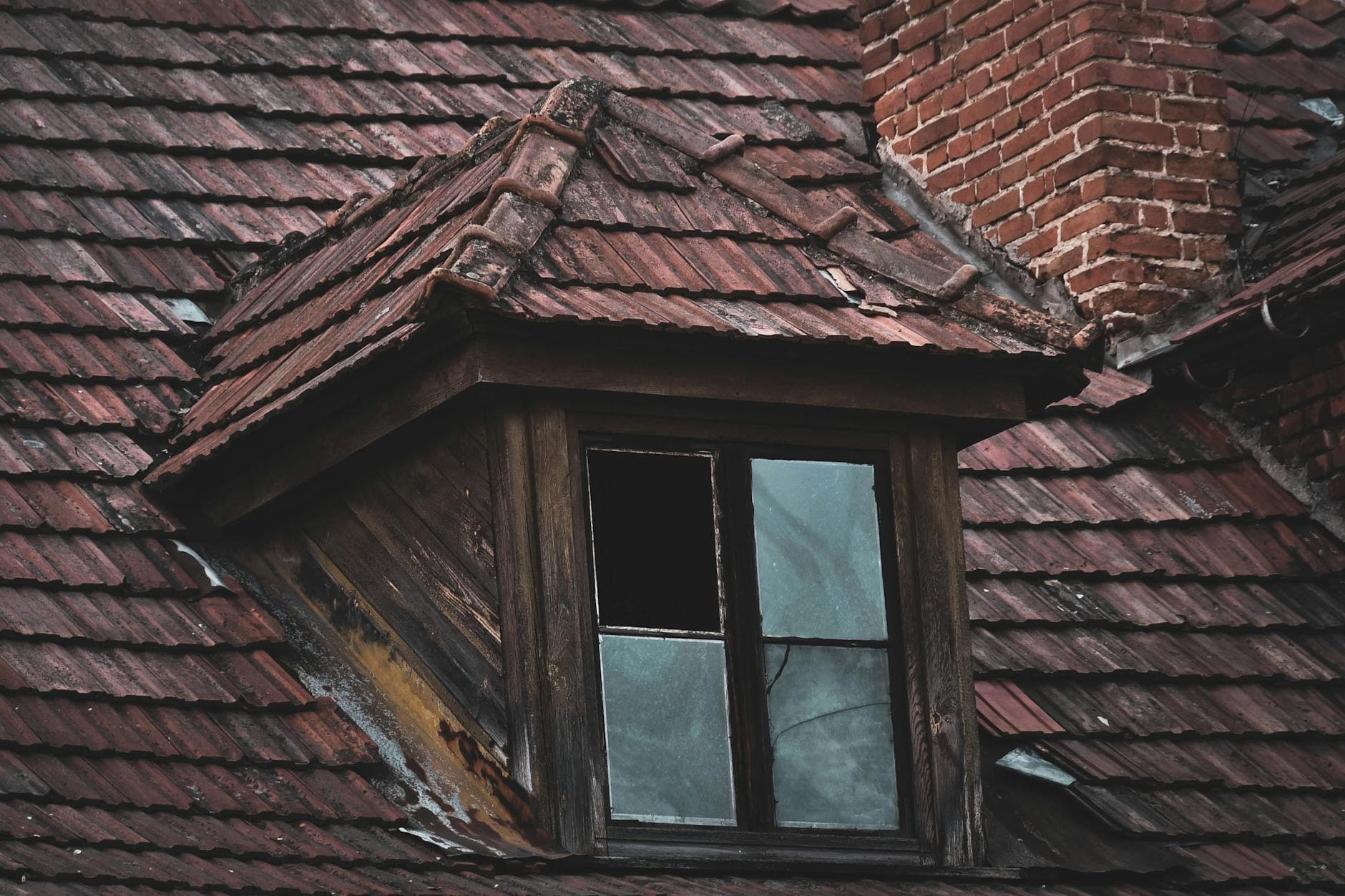 A weathered window on a textured red-tiled roof in Kazimierz Dolny, Poland.